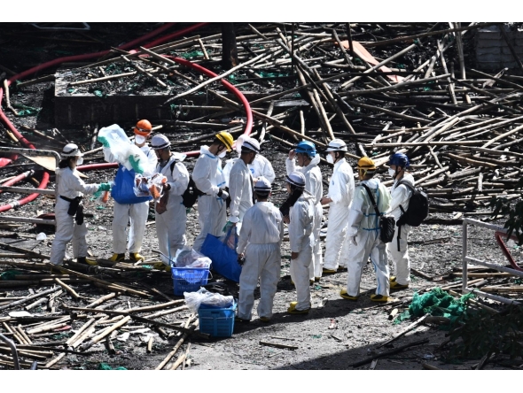 Police officers from the Disaster Victim Identification Unit (DVIU), dressed in white-coloured full-body protective gear, enter one of the housing blocks of Wang Fuk Court in the aftermath of the deadly November 26 fire, in Hong Kong on November 29, 2025. (Photo by Philip FONG / AFP)

