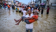 A youth carries an elderly man as they wade through a flooded street after heavy rainfall in Wellampitiya on the outskirts of Colombo on November 30, 2025. (Photo by Ishara S. KODIKARA / AFP)
