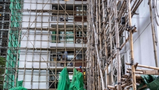 A construction worker removes the netting of bamboo scaffolding at Sui Wo Court housing estate in Fo Tan district of Hong Kong on December 4, 2025. (Photo by Philip Fong / AFP)
