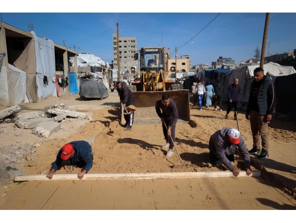 Palestinian municipality workers repair a road damaged during the war in the Nuseirat camp for the displaced in the central Gaza Strip on December 22, 2025. (Photo by Eyad Baba / AFP)