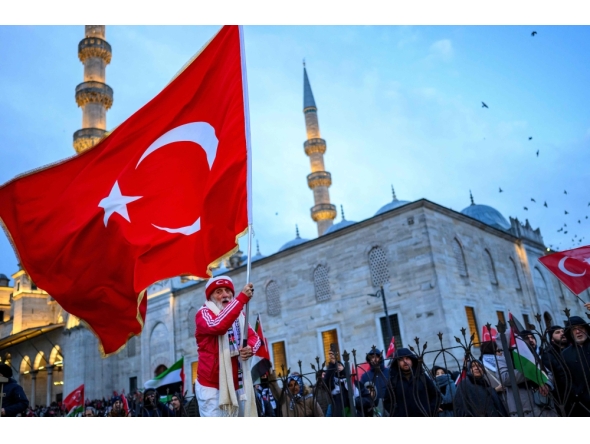 A man waves a Turkish flag as people demonstrate in solidarity with the Palestinian people amid the ongoing war in the Gaza  at the Galata Bridge in Istanbul on January 1, 2026. (Photo by Yasin Akgul / AFP)