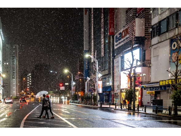 Pedestrians walk with umbrellas as it snows and rains in Tokyo's Akihabara district on January 2, 2026. (Photo by Philip FONG / AFP)

