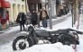 Passers-by walk past a snow-covered motorcycle in the center of Kyiv on January 10, 2026. (Photo by Sergei SUPINSKY / AFP)
