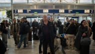 Passengers check screens for flight information as traffic is delayed or reported due to technical issues at a departure hall of Athens' Eleftherios Venizelos international airport in Spata near Athens, on January 4, 2025. Photo by Angelos Tzortzinis / AFP 
