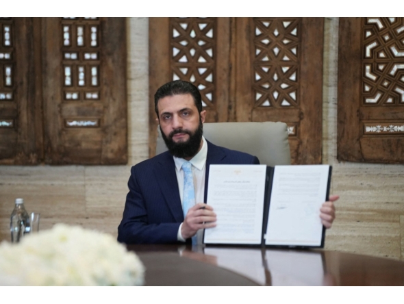 Syria's President Ahmed al-Sharaa signs an agreement at the Presidential Palace in Damascus on January 18, 2026. (Photo by Rami al SAYED / AFP)
