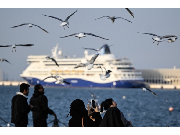 A woman uses her mobile phone to take pictures of the seagulls at the old seaport in Doha on January 20, 2026. (Photo by MAHMUD HAMS / AFP)
