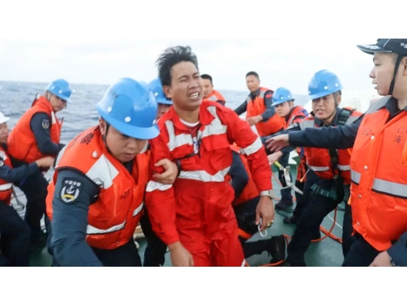 This handout from the Chinese Coast Guard taken and released by the Chinese embassy in Manila on January 23, 2026 shows Chinese Coast Guard personnel assisting a rescued Filipino crew member of a capsized cargo ship near the contested Scarborough Shoal in the South China Sea. Photo by Handout / various sources / AFP
