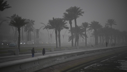 People dressed in winter clothes take a stroll as strong northwesterly winds brought temperatures down in Qatar yesterday.
