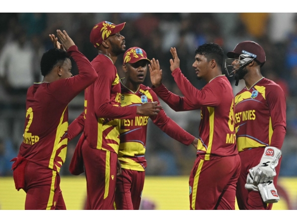 West Indies' Gudakesh Motie celebrates with teammates after taking the wicket of England's captain Harry Brook during the 2026 ICC Men's T20 Cricket World Cup group stage match between England and West Indies at the Wankhede Stadium in Mumbai on February 11, 2026. (Photo by Indranil MUKHERJEE / AFP)

