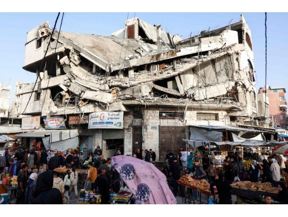 Palestinians shop for food beneath a destroyed building in Gaza City's Zawiya market on February 18, 2026, on the first days of the holy fasting month of Ramadan. (Photo by Omar AL-QATTAA / AFP)