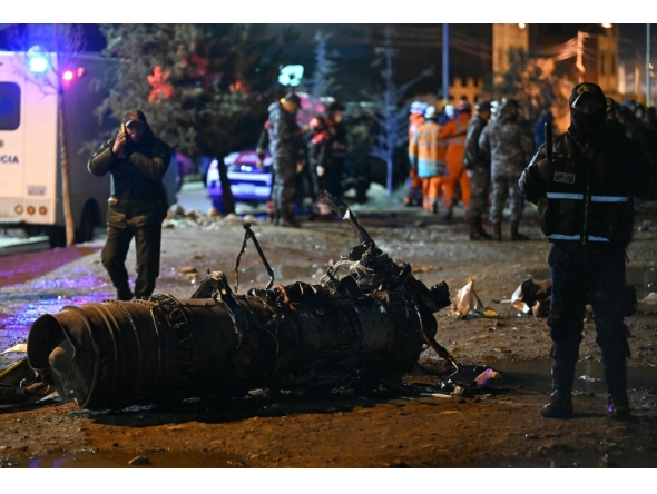 Military personnel stand next to pieces of a military plane that crashed in el Alto, near La Paz on February 27, 2026. At least 11 people were killed on February 27 when a Bolivian military cargo plane carrying banknotes crashed while landing near the capital city La Paz, prompting police to repel bystanders grabbing cash. (Photo by Aizar Raldea / AFP)