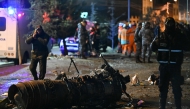 Military personnel stand next to pieces of a military plane that crashed in el Alto, near La Paz on February 27, 2026. At least 11 people were killed on February 27 when a Bolivian military cargo plane carrying banknotes crashed while landing near the capital city La Paz, prompting police to repel bystanders grabbing cash. (Photo by Aizar Raldea / AFP)