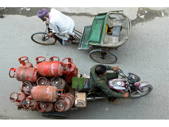 A delivery man transports liquid petroleum gas (LPG) cylinders in Amritsar on March 24, 2026. Photo by Narinder Nanu / AFP

