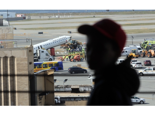 A child looks out at an Air Canada Express plane that collided Sunday night with a fire truck on the tarmac at LaGuardia Airport on March 25, 2026 in New York City. Photo by SPENCER PLATT / GETTY IMAGES NORTH AMERICA / Getty Images via AFP