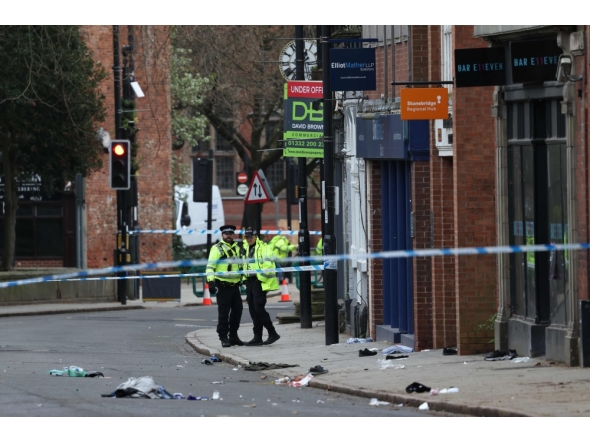 Police officers work near to a variety of personal items seen covering the road inside a cordon set up on Friar Gate in central Derby, central England on March 29, 2026. (Photo by Darren Staples / AFP)