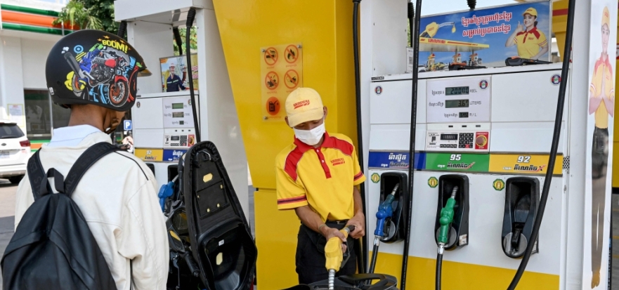 An employee pumps gasoline into the motorbike of a customer at a fuel station in Phnom Penh on April 1, 2026. (Photo by Tang Chhin Sothy / AFP)