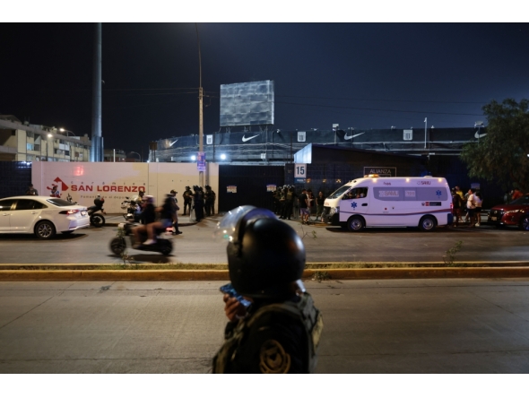 Police officers stand guard at the entrance of the Alejandro Villanueva Stadium while relatives wait for news after an accident in the stands in Lima on April 3, 2026. (Photo by Connie FRANCE / AFP)
