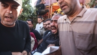 A Palestinian man reacts as he and others carry the body of a victim at the Nasser Hospital following an Israeli airstrike in the city of Khan Yunis, in the southern Gaza Strip on April 21, 2026. (Photo by Bashar Taleb / AFP)