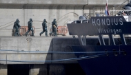 Persons wearing protective suits walk toward the hantavirus-stricken cruise ship MV Hondius docked in the port of Granadilla de Abona on the island of Tenerife in Spain's Canary Islands on May 11, 2026. (Photo by JORGE GUERRERO / AFP)