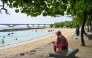 A man sits under a tree as it rains at Artificial Beach in Malé on May 15, 2026. Photo by MOHAMED AFRAH / AFP