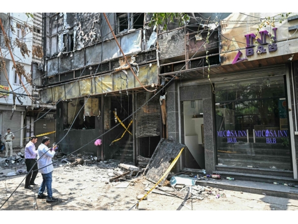 Forensics team members take photographs of the site following a fire that broke out at a hotel in New Delhi (Photo by Arun Sankar / AFP)