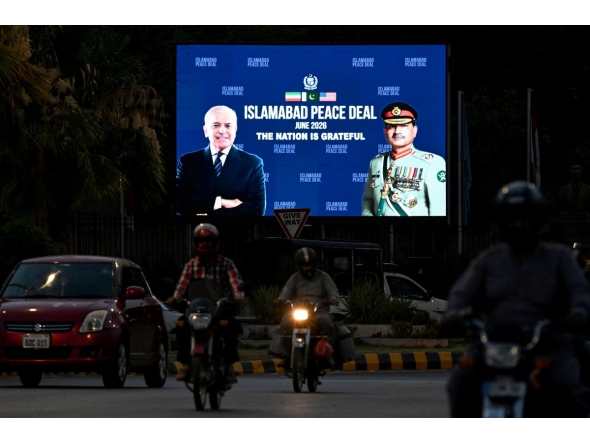 Commuters ride past an electronic board featuring Pakistan's Prime Minister Shehbaz Sharif (L) with Army Chief and Field Marshal Syed Asim Munir, displayed along a road in Islamabad on June 18, 2026 after the US–Iran peace deal announcement. Photo by Aamir Qureshi / AFP