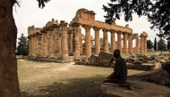 (Files) A man sits in the shade in front of the Temple of Zeus at the archaeological site of Cyrene, near the town of Shahat on Libya's northeastern Mediterranean coast, on May 18, 2026. (Photo by Abdullah Doma / AFP)