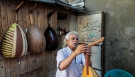 Displaced Palestinian craftsman Suhail Abu Shawish tunes a Oud musical instrument at his makeshift workshop in the Nuseirat camp for Palestinian refugees in the central Gaza Strip on June 23, 2026. (Photo by Eyad Baba / AFP)