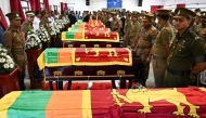 Security personnel pay tribute as they stand next to coffins of seven guards killed during Negombo prison riot in Colombo July 8, 2026. (Photo by Ishara S. Kodikara / AFP)