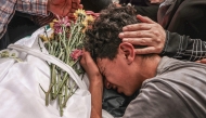 A relative mourns over the body of 17-year-old Fadi al-Naasan during his funeral in the village of Al-Mughayyir, east of Ramallah in the Israeli-occupied West Bank, on July 18, 2026. (Photo by JAAFAR ASHTIYEH / AFP)