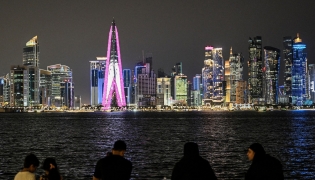 People sit facing the high-rise buildings at the Doha corniche promenade on July 21, 2026. (Photo by Mahmud Hams / AFP)
