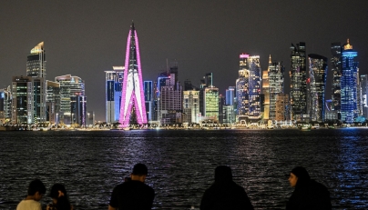 People sit facing the high-rise buildings at the Doha corniche promenade on July 21, 2026. (Photo by Mahmud Hams / AFP)
