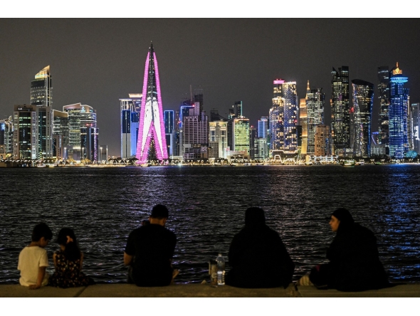 People sit facing the high-rise buildings at the Doha corniche promenade on July 21, 2026. (Photo by Mahmud Hams / AFP)
