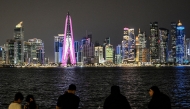 People sit facing the high-rise buildings at the Doha corniche promenade on July 21, 2026. (Photo by Mahmud Hams / AFP)
