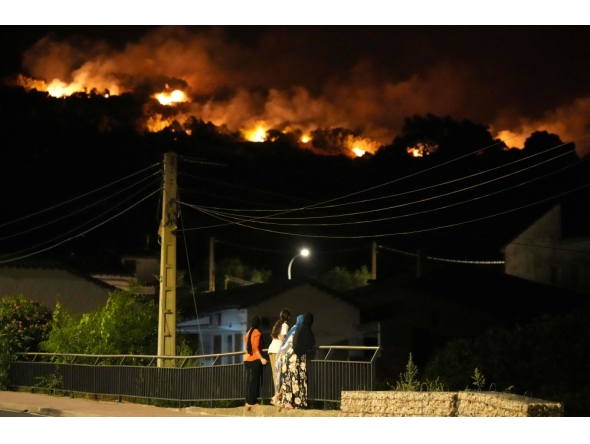 Residents watch the flames on hill crests as firefighters battle a wildfire in Cebreros area, near Avila, 80 kms west of Madrid at night on July 24, 2026. (Photo by Cesar MANSO / AFP)