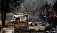 Burned cars sit in the yard of a home after a wildfire raged through Pelayos de la Presa, 65 kilometers west of Madrid, on July 26, 2026. (Photo by Oscar Del Pozo / AFP)
