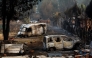 Burned cars sit in the yard of a home after a wildfire raged through Pelayos de la Presa, 65 kilometers west of Madrid, on July 26, 2026. (Photo by Oscar Del Pozo / AFP)