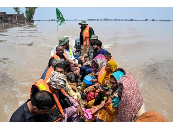 People sitting on a rescue boat ride through a flooded area after heavy monsoon rains induced a rise in the water level of the River Ravi in Muridke on July 27, 2026. (Photo by Arif ALI / AFP)