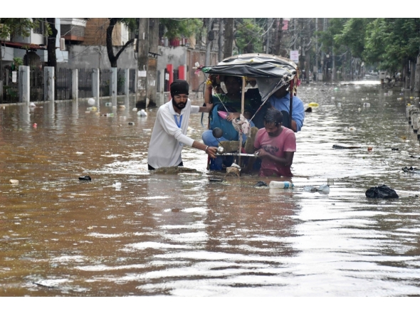 Residents wade through a flooded street following heavy monsoon rains in Guwahati on August 4, 2026. (Photo by Biju BORO / AFP)