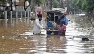 Residents wade through a flooded street following heavy monsoon rains in Guwahati on August 4, 2026. (Photo by Biju BORO / AFP)