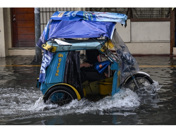 A tricycle wades through a flooded street due to heavy rains brought by the southwest monsoon in Manila on August 9, 2026. (Photo by Jam STA ROSA / AFP)