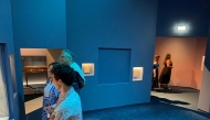 Visitors look at exhibits near a blue panel covering the area where a display case was smashed and a Van Cleef and Arpels necklace was stolen at Vienna's Museum of Applied Arts (MAK), in Vienna, Austria, on August 28, 2026. Photo by Jeremy AUDOUARD / AFP