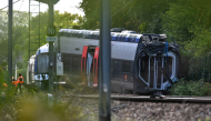 SNCF workers stand next to a derailed train carriage in Cléon, northwestern France, on September 12, 2026, the morning after the train derailed. (Photo by Guillaume Saligot / AFP)