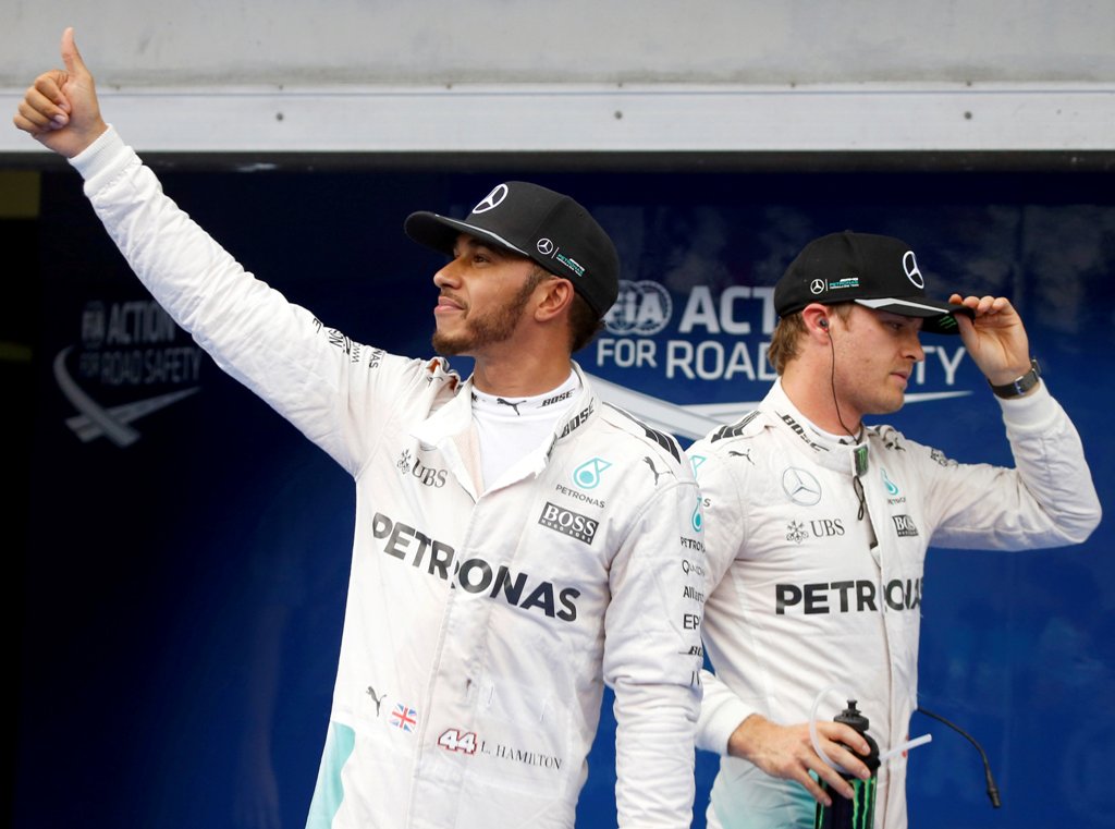 Mercedes' Lewis Hamilton of Britain celebrates pole position as Mercedes' Nico Rosberg of Germany walks by. REUTERS/Edgar Su
