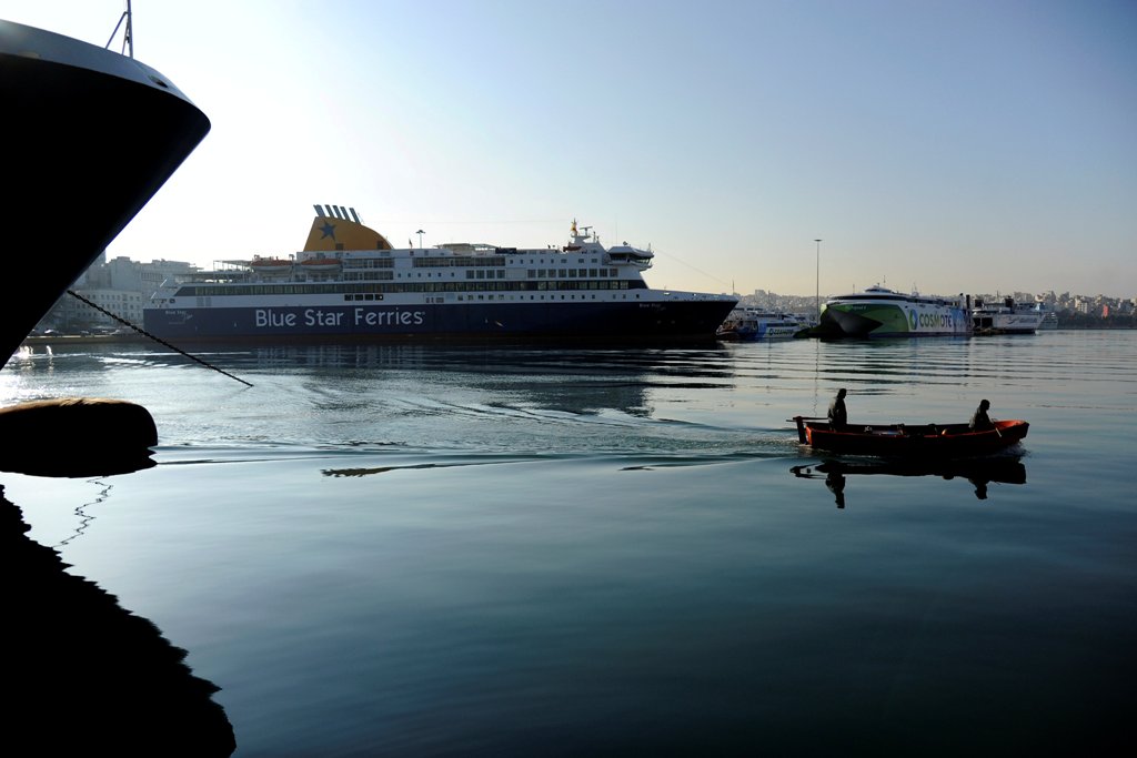 A boat passes by moored passenger ships during a 24-hour strike by Greek ship workers against government policies affecting their sector at the port of Piraeus, near Athens, Greece, November 24, 2016. REUTERS/Michalis Karagiannis