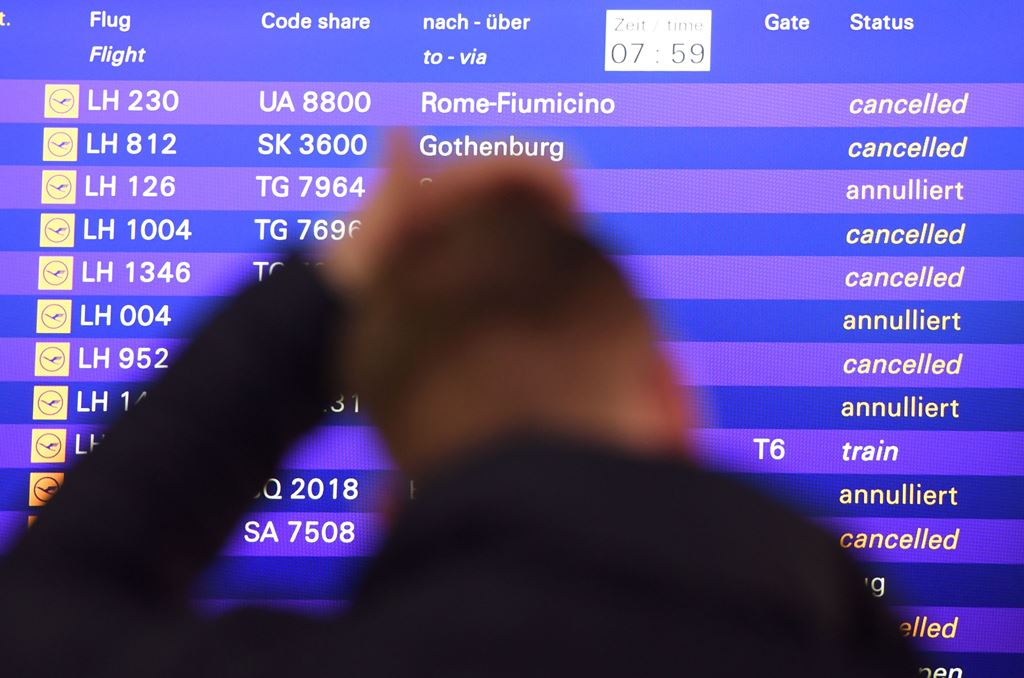 A flight passenger stands in front of a board displaying cancelled flights of German airline Lufthansa on November 25, 2016 at the airport in Frankfurt am Main, western Germany. Germany OUT / AFP / dpa / Arne Dedert