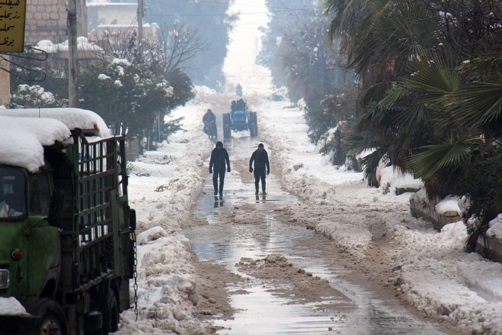 Syrians walk in a snow covered street in the town of Maaret al-Numan, in Syria's northern province of Idlib, on December 22, 2016. AFP / GHAITH OMRAN
