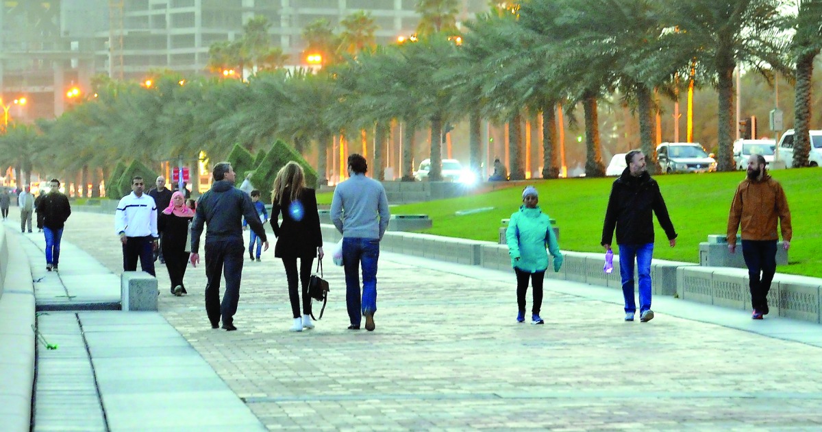 Fitness enthusiasts in warm clothing walk along the Doha Corniche during a windy and cold evening yesterday. Pic: Kammutty VP / The Peninsula