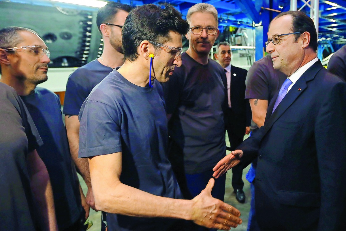 French President Francois Hollande (right) talks to workers as he visits the turbines production unit of the General Electric plant in Belfort