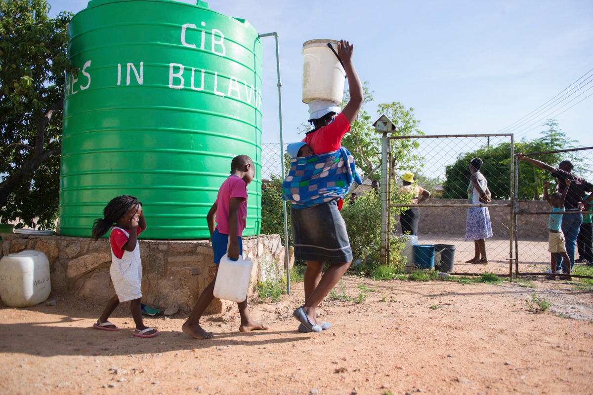 A woman and her children carrying water cans fetched from a tank installed at a church in Luveve on the outskirts of Bulawayo on November 24, 2016 (AFP / Zinyange Auntony)  